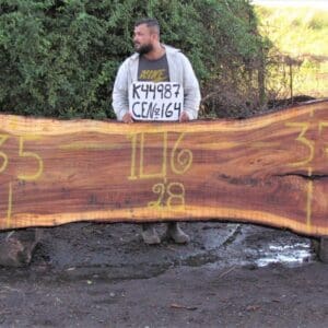 Man holding sign behind large wooden slab.